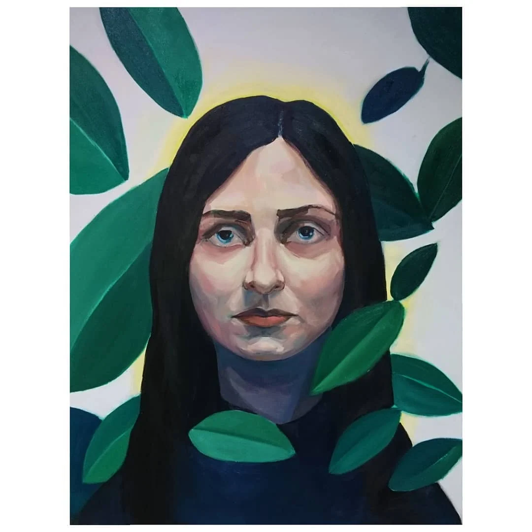 Portret osoby o ciemnych włosach otoczonej zielonymi liśćmi na jasnym tle, przedstawiony na obrazie „Amazonia Bolesna”.