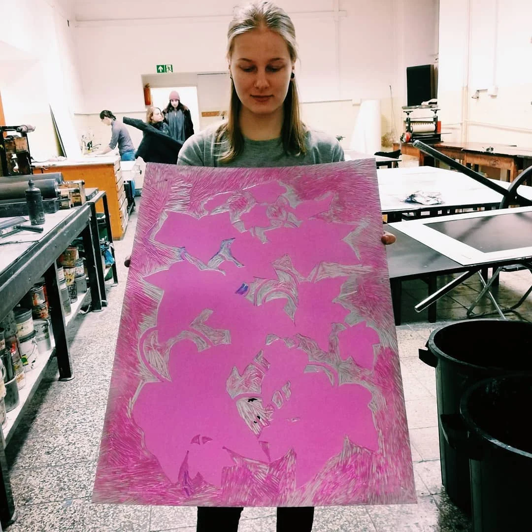 Klara Keczyńska trzyma dużą różową matrycę linorytniczą z wyciętym botanicznym wzorem w pracowni graficznej.