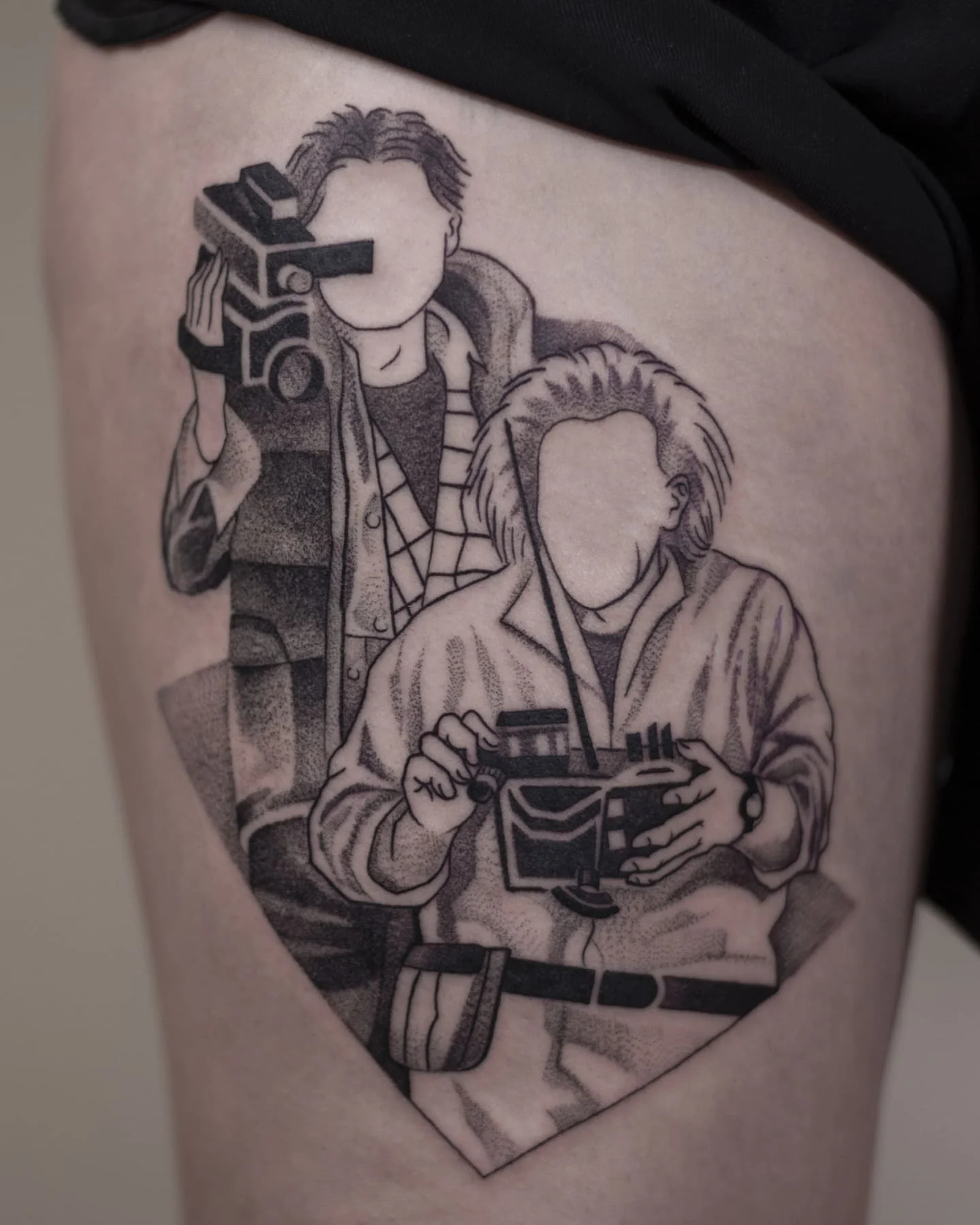 Tatuaż przedstawiający dwie postacie z filmu „Powrót do przyszłości”, kamerę oraz rekwizyty związane z podróżą w czasie.