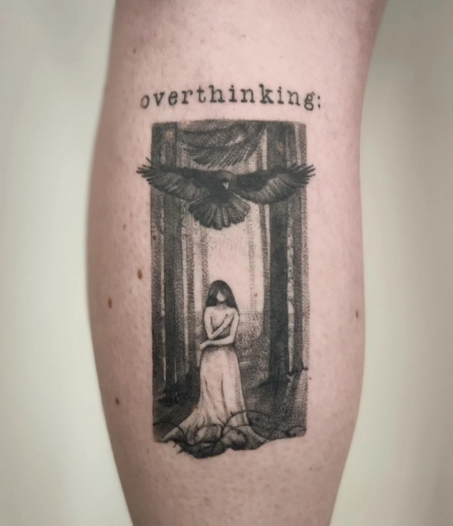 Wygojona kompozycja dwóch czarno-szarych tatuaży na nogach: leśne sceny z postaciami, ptakiem i jeleniem oraz napisy „overthinking” i „open-minded”., zdjęcie 2 z 4