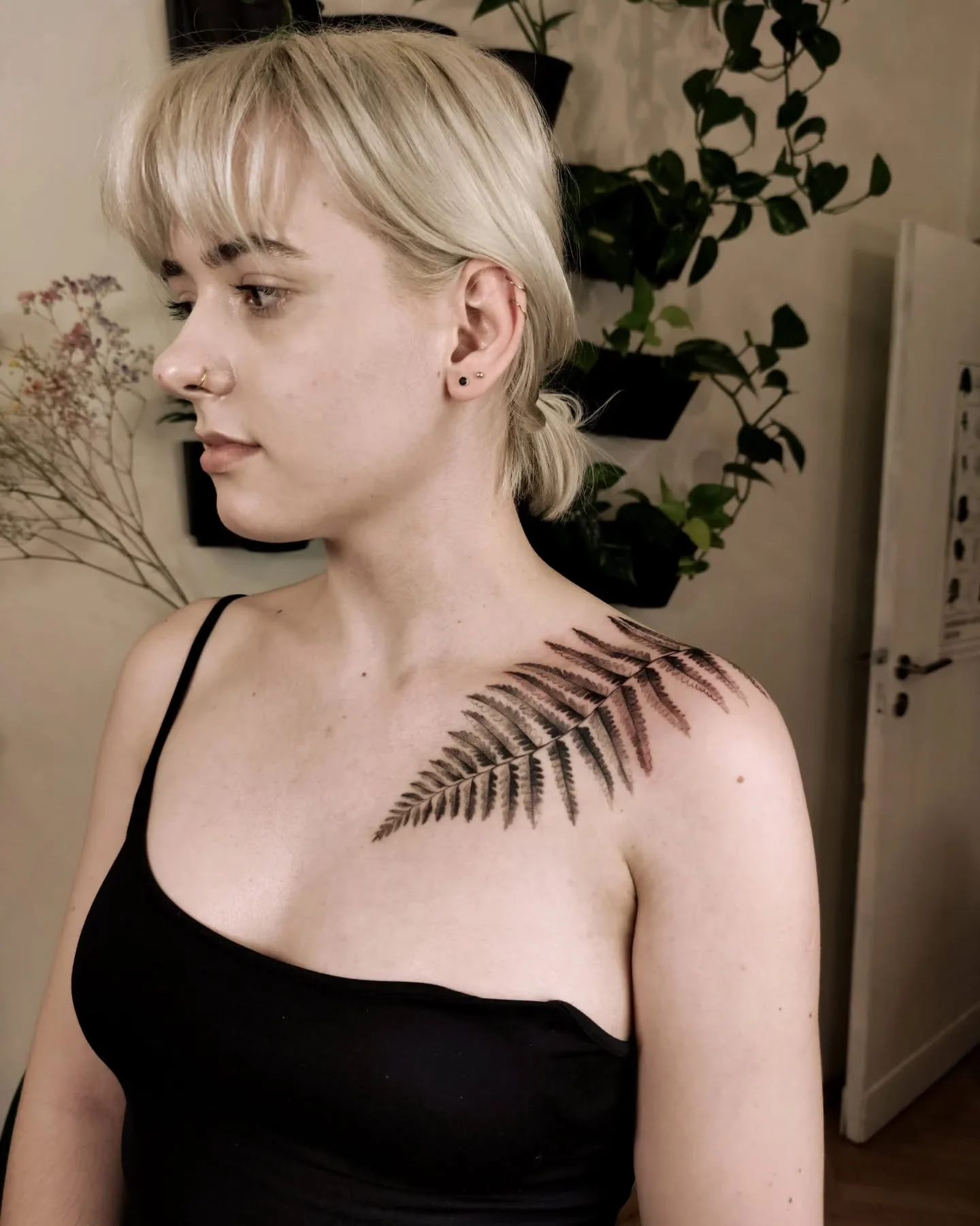 Wygojony tatuaż paproci na obojczyku i ramieniu modelki, pokazany z kilku perspektyw., zdjęcie 1 z 5