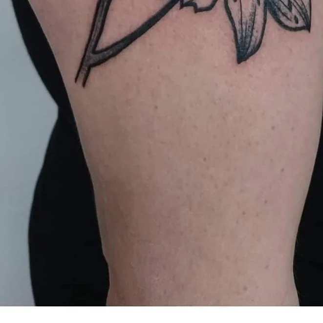 Zbliżenie fragmentu botanicznego tatuażu w czarnym tuszu na skórze.