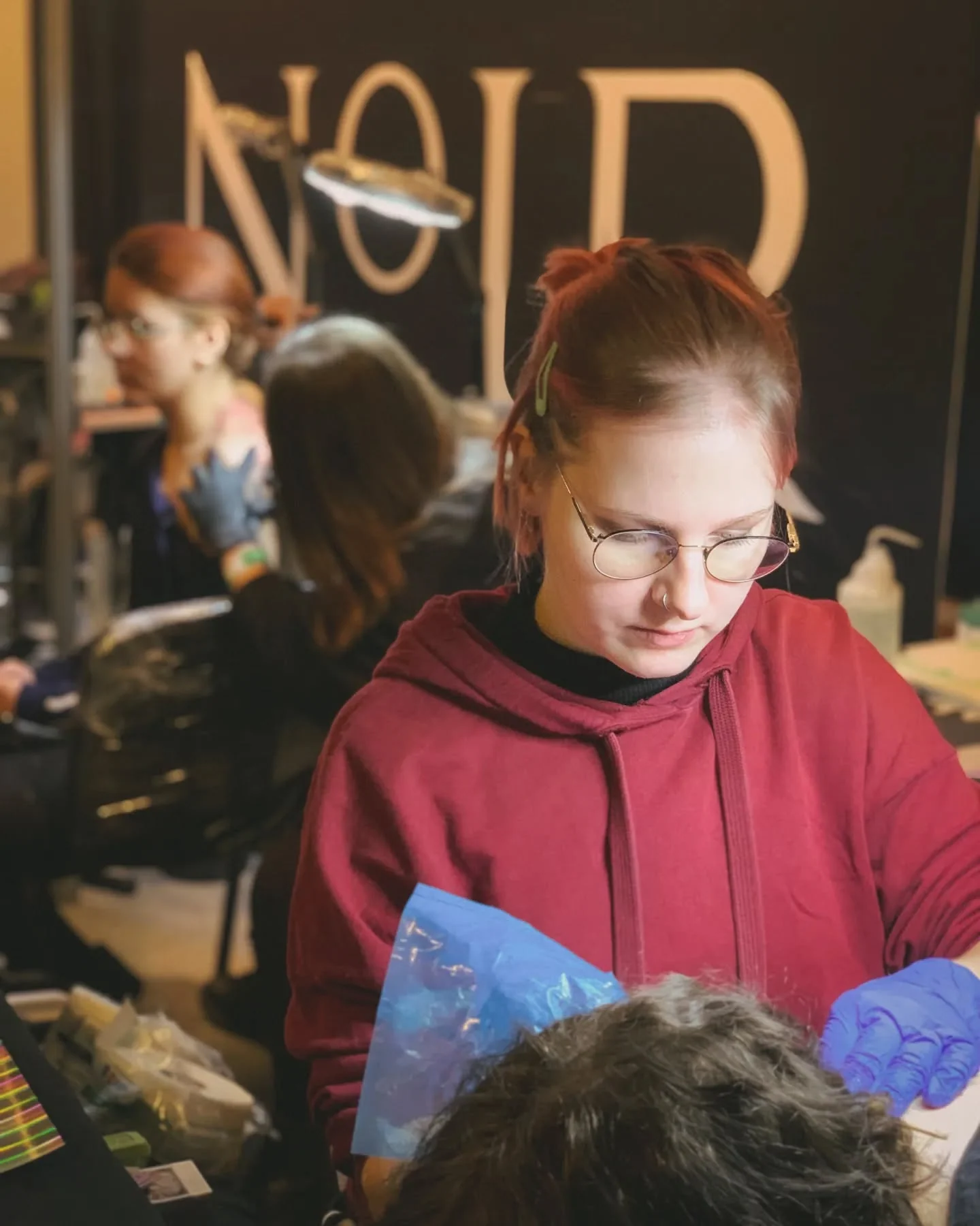 Klara Keczyńska tatuuje klienta podczas konwentu tatuażu, pracując w rękawiczkach przy stanowisku.