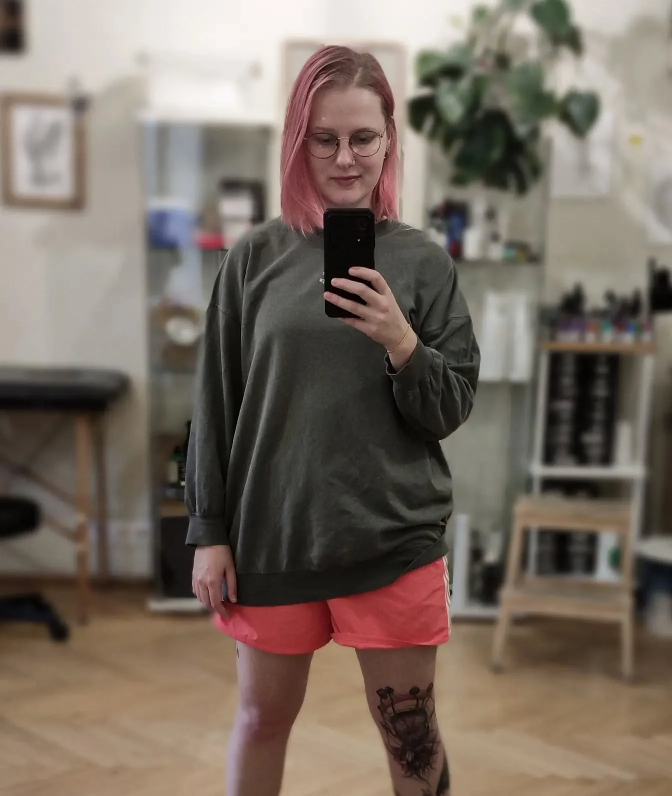 Klara Keczyńska wykonuje lustrzane zdjęcie w pracowni; na jednej nodze widoczny jest tatuaż.