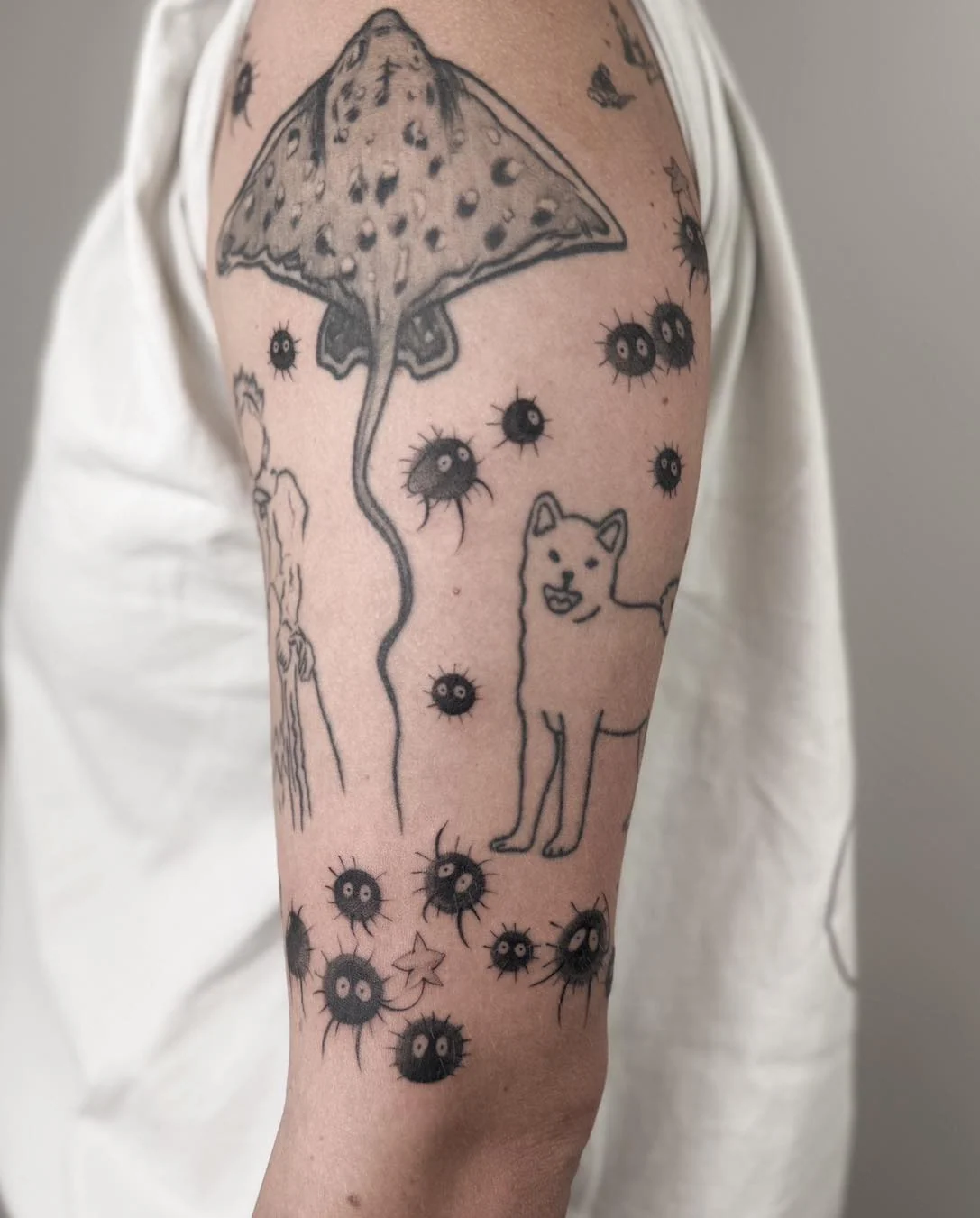 Wygojony tatuaż na ramieniu przedstawiający Calcifera oraz małe czarne kurzyki inspirowane filmami Studia Ghibli., zdjęcie 4 z 4
