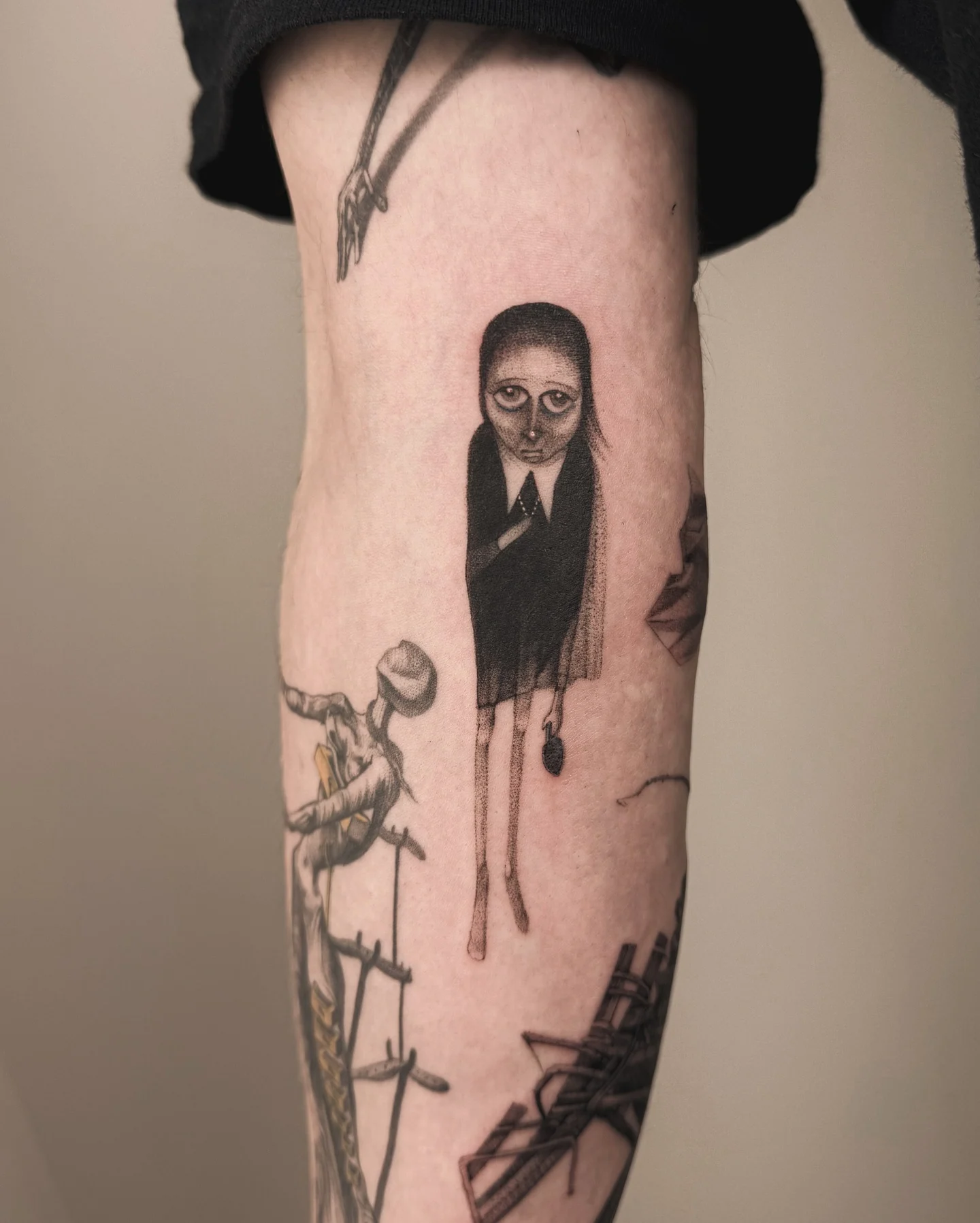 Karuzela przedstawia czarno-szare tatuaże na ludzkiej skórze, w tym figurę o zdeformowanej sylwetce, mniejszy kompozycyjny motyw na ramieniu oraz większą kompozycję na plecach., zdjęcie 4 z 12