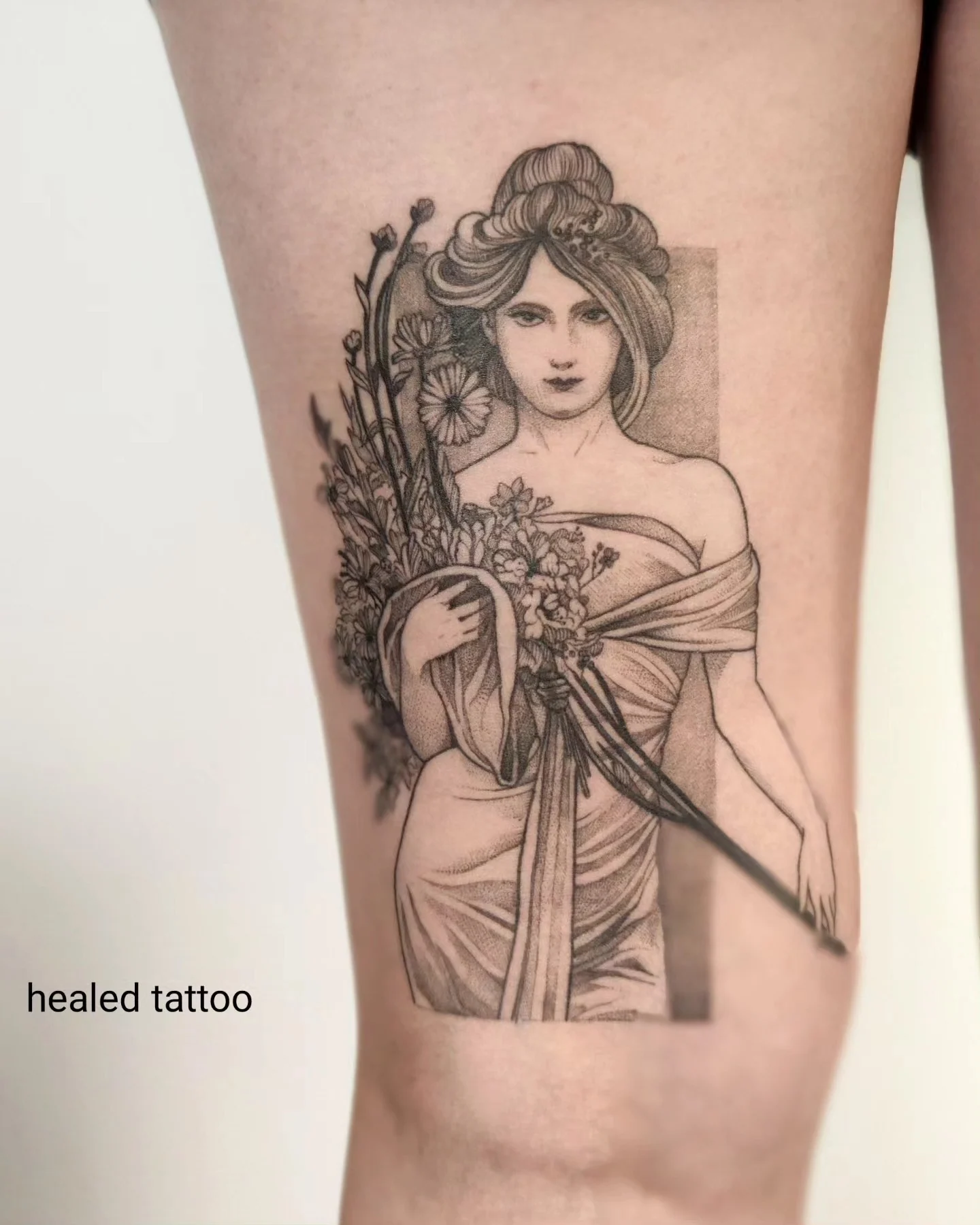 Wygojony tatuaż na nodze przedstawiający kobietę w stylu art nouveau z kwiatami i bukietem, pokazany obok projektu referencyjnego oraz w zbliżeniu., zdjęcie 2 z 6