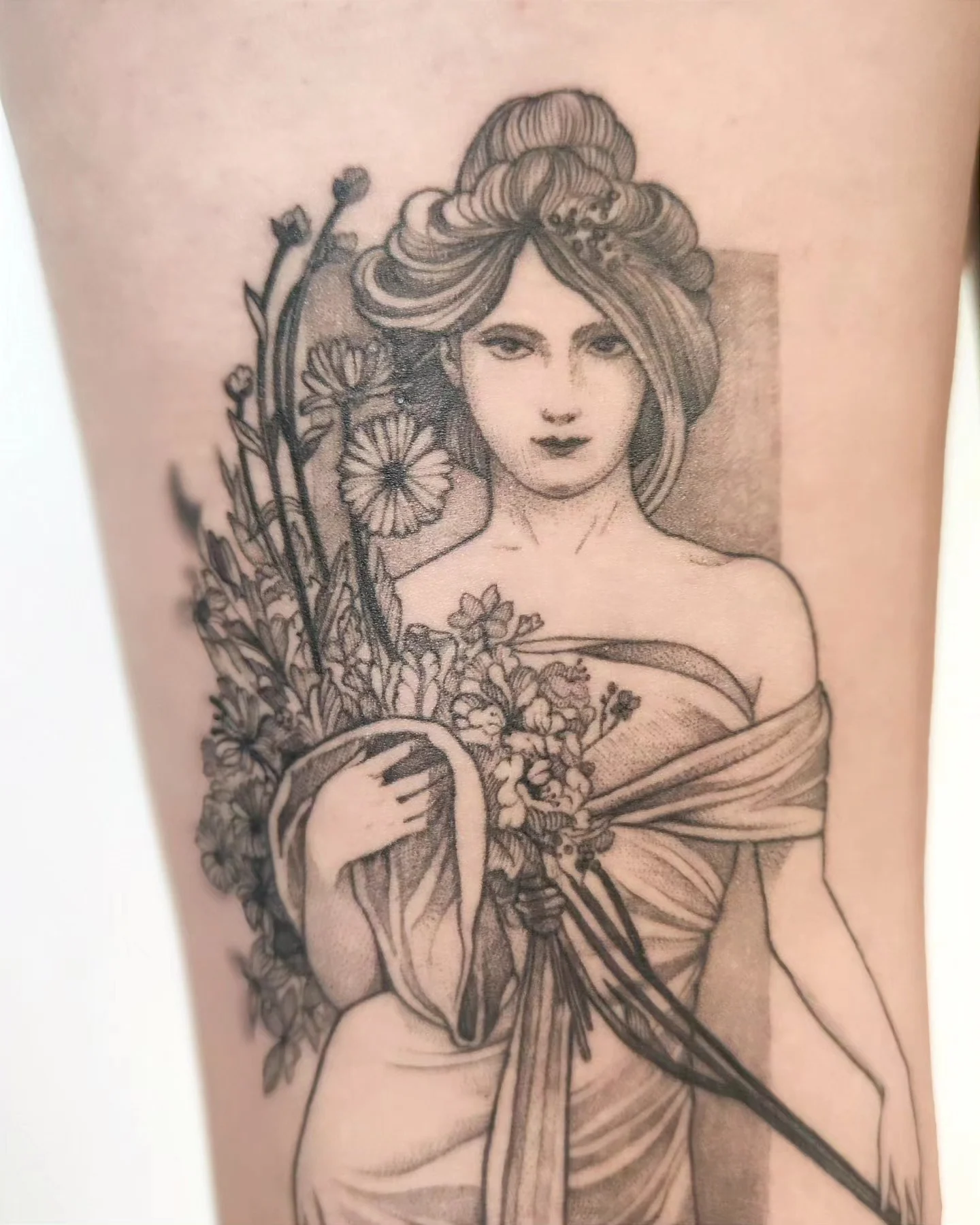 Wygojony tatuaż na nodze przedstawiający kobietę w stylu art nouveau z kwiatami i bukietem, pokazany obok projektu referencyjnego oraz w zbliżeniu., zdjęcie 3 z 6