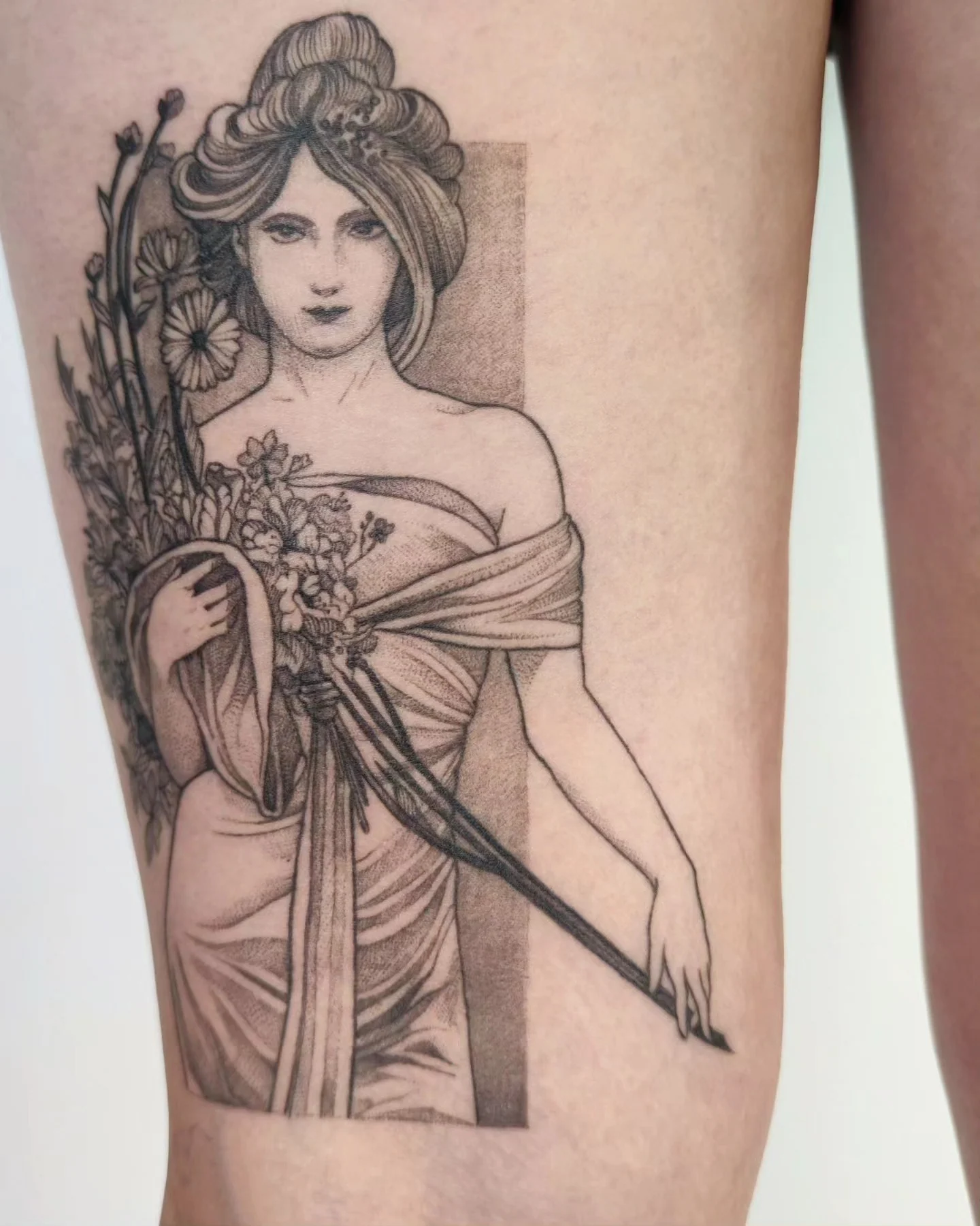 Wygojony tatuaż na nodze przedstawiający kobietę w stylu art nouveau z kwiatami i bukietem, pokazany obok projektu referencyjnego oraz w zbliżeniu., zdjęcie 4 z 6