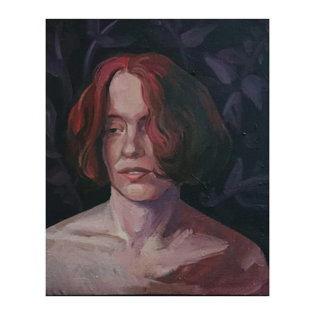 Portret osoby z rudymi włosami na ciemnym tle z fioletowymi roślinami.