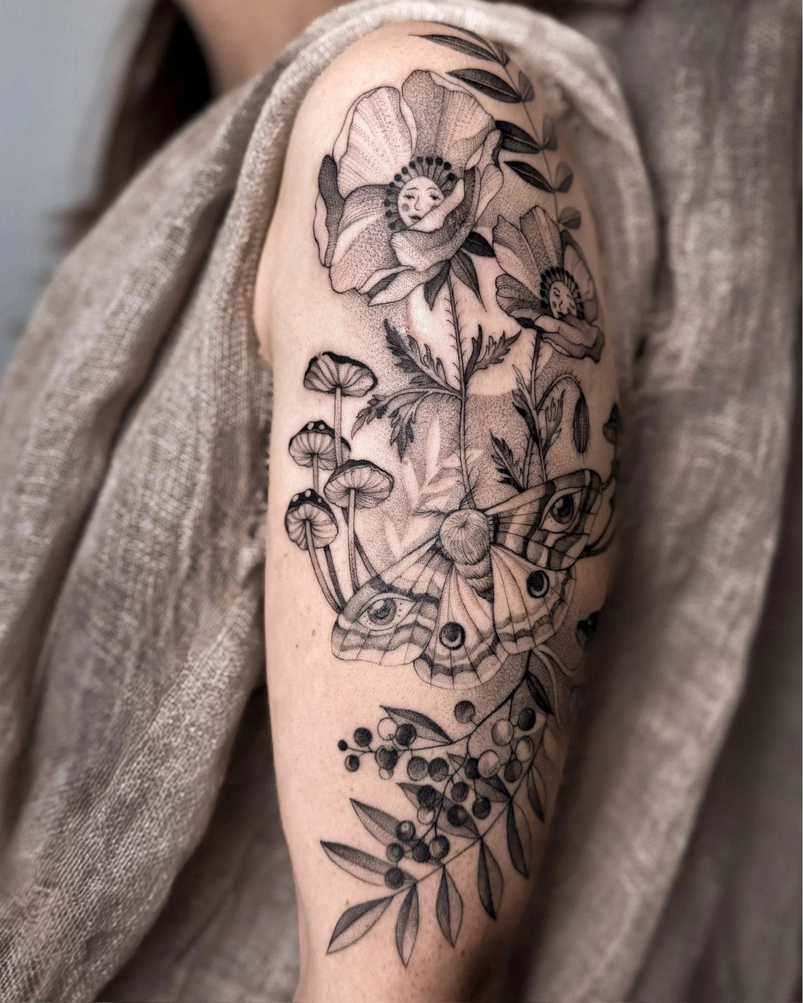 Botaniczna kompozycja tatuażu na ramieniu, przedstawiająca kwiaty maku, śpiące laleczki, ćmę, grzyby i gałązkę jarzębiny., zdjęcie 2 z 3