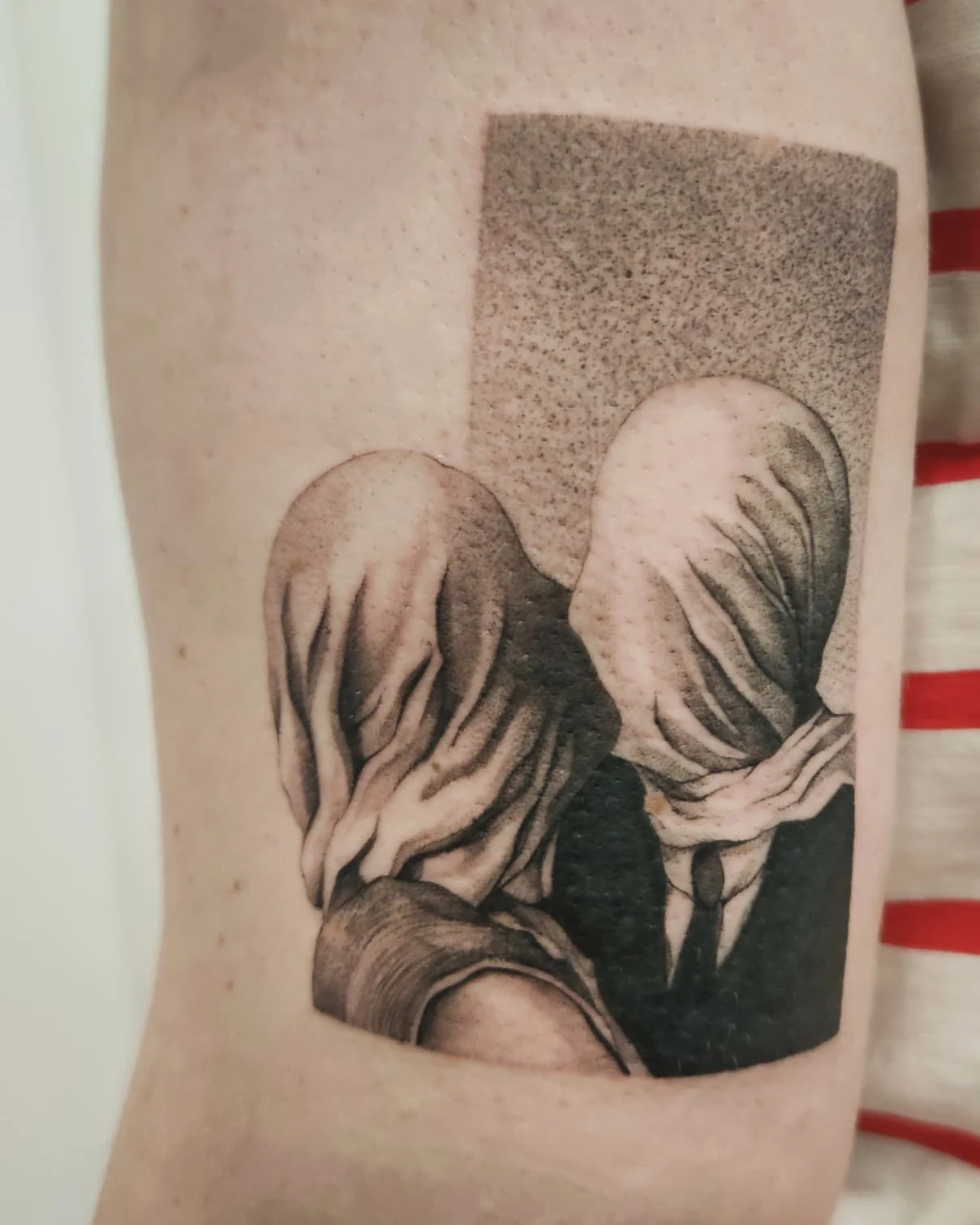 Zbliżenia tatuażu przedstawiającego dwie postacie z zasłoniętymi twarzami, inspirowanego obrazem „Kochankowie” René Magritte’a., zdjęcie 3 z 4