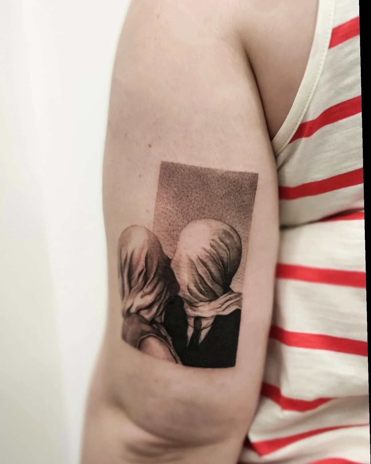 Zbliżenia tatuażu przedstawiającego dwie postacie z zasłoniętymi twarzami, inspirowanego obrazem „Kochankowie” René Magritte’a., zdjęcie 4 z 4