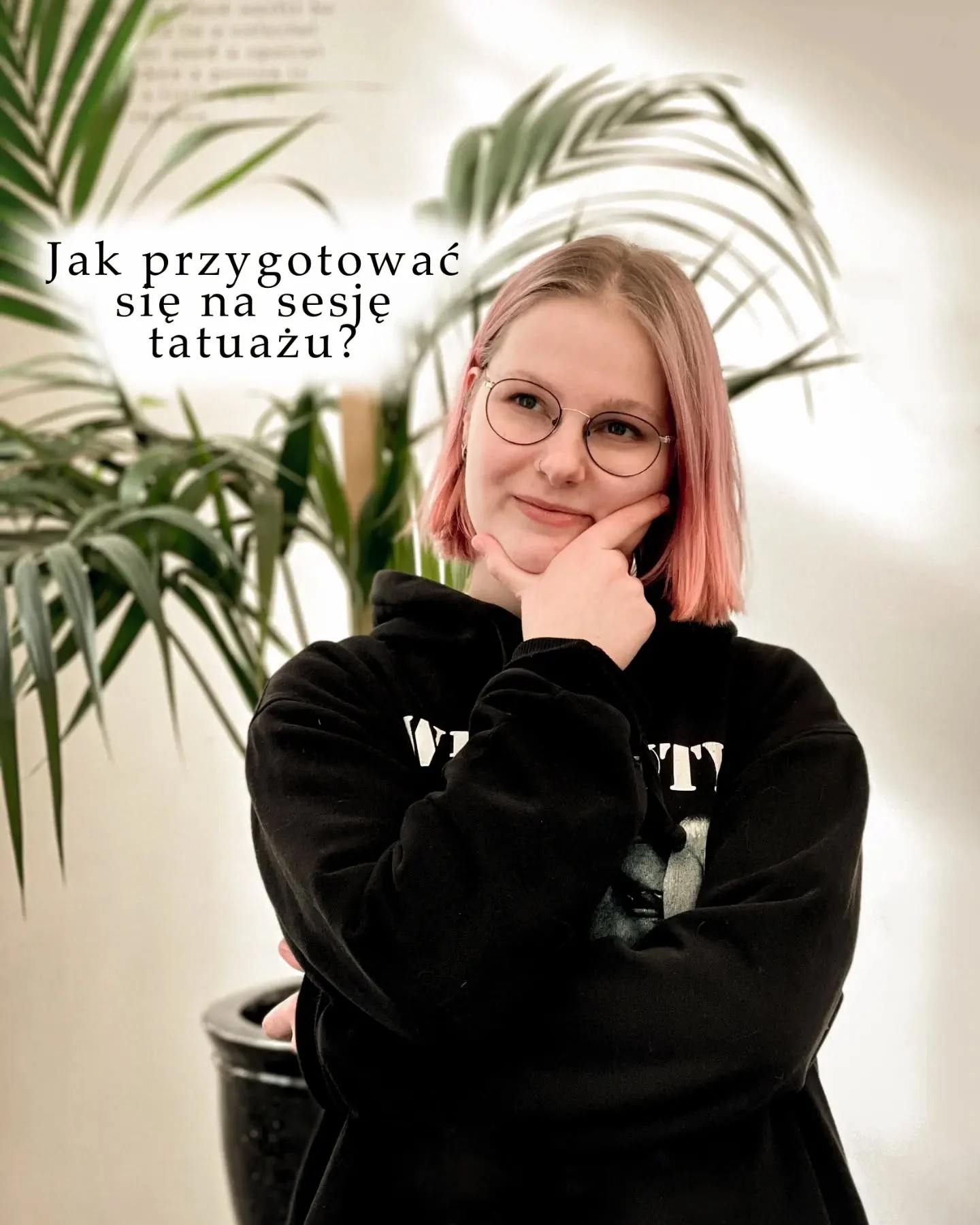 Klara Keczyńska w czarnej bluzie pozuje przed roślinami; na obrazie widnieje napis „Jak przygotować się na sesję tatuażu?”.